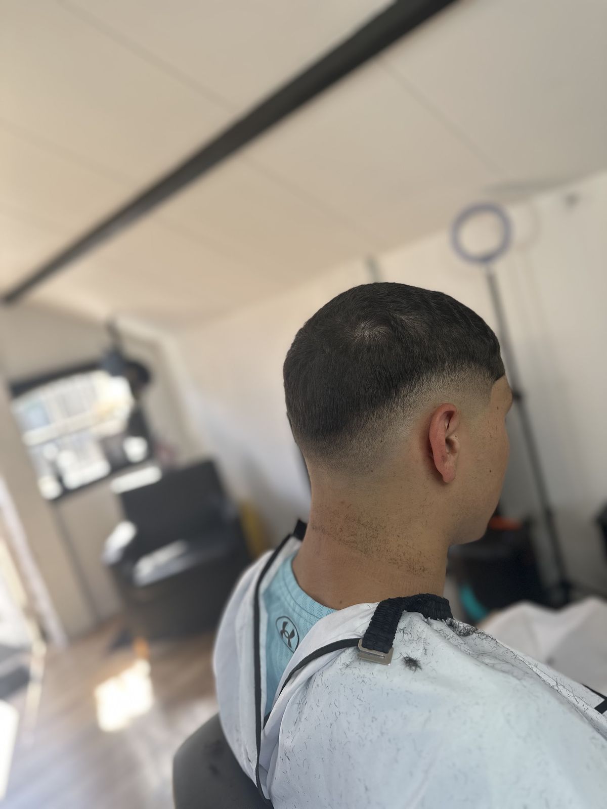 Zijkant van een korte fade op donker haar, met witte kapmantel